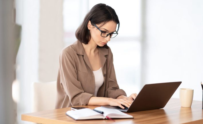 woman in spectacles working on her laptop