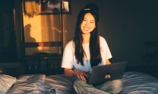 woman sitting on the bed with her laptop