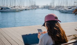 a woman sitting on the bench while working on her laptop