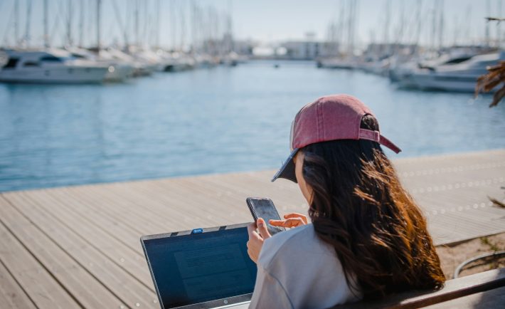 a woman sitting on the bench while working on her laptop