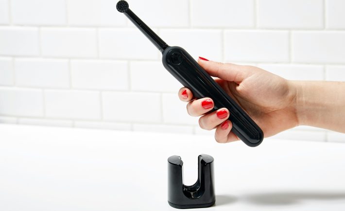a person holding a black electric toothbrush