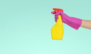 person holding a yellow spray bottle with pink gloves