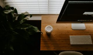 White coffee cup beside an iMac