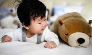 infant beside a plush toy