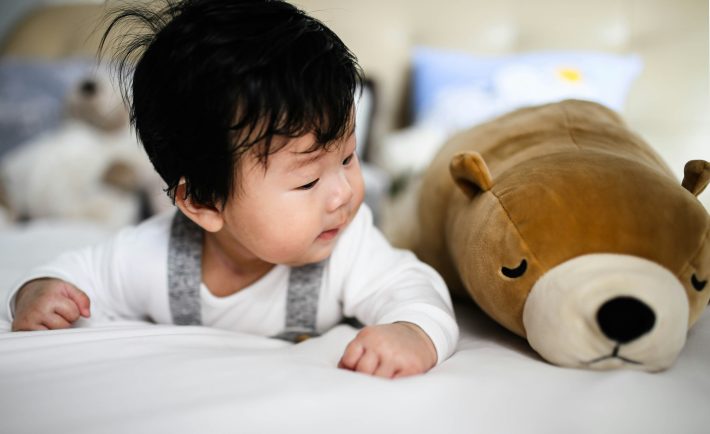 infant beside a plush toy