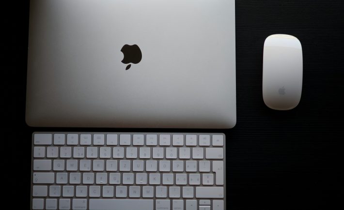 Apple laptop, keyboard & mouse on a black surface