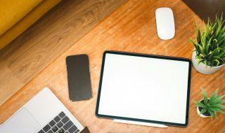 a work desk with a tablet, mouse, and phone