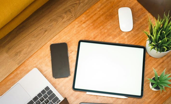 a work desk with a tablet, mouse, and phone