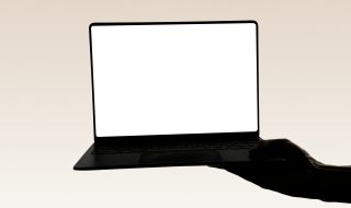 a hand holding a laptop with a white screen