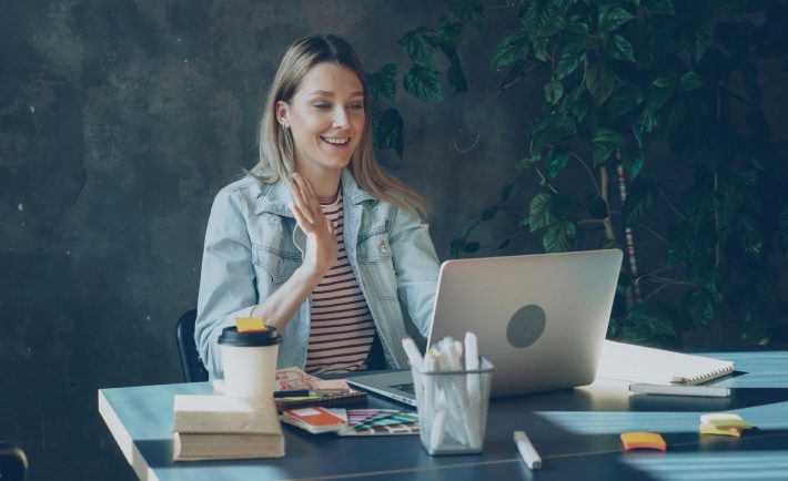 woman waving to her laptop screen